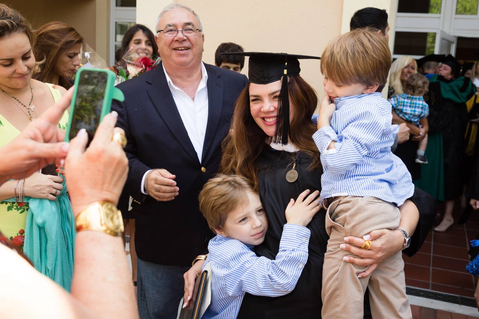 A Rollins College graduate hugs children at commencement.