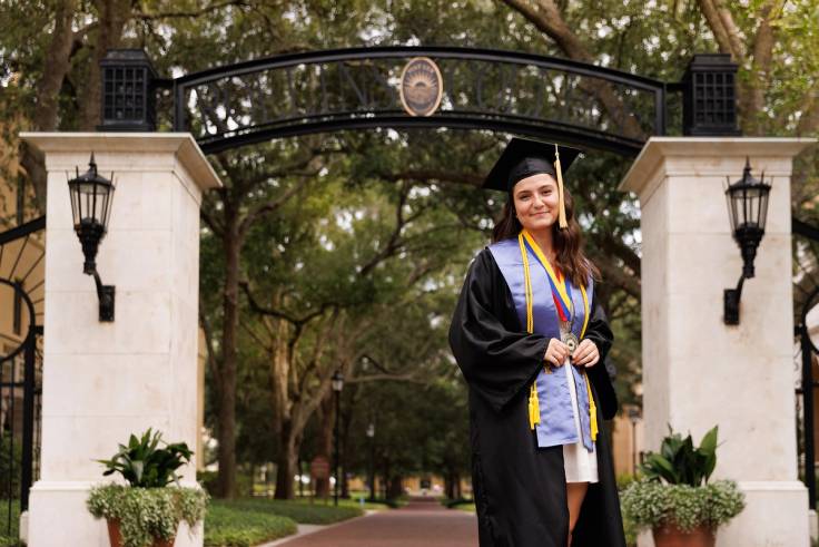 Capri Gutierrez in her cap and gown on the Rollins campus.