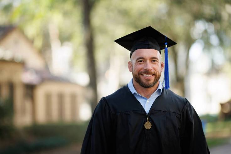 Eric Reichwein poses for a portrait in a cap and gown.