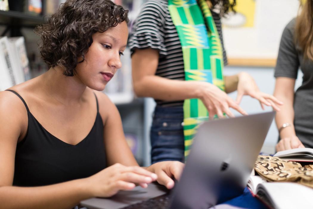 A Rollins student types on their computer while studying African textiles.