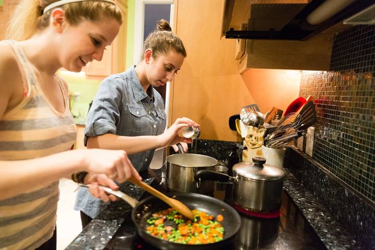 Students cooking a meal together in their dorm room.