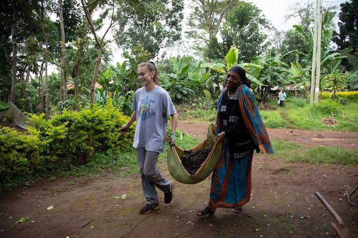 A Rollins student helps a local resident carry supplies.