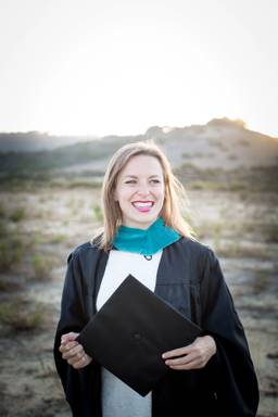 Brenna McKee ’15 pictured with her diploma in a desert scene.
