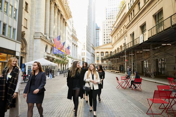 A group of female college students walk through the financial district in New York City.