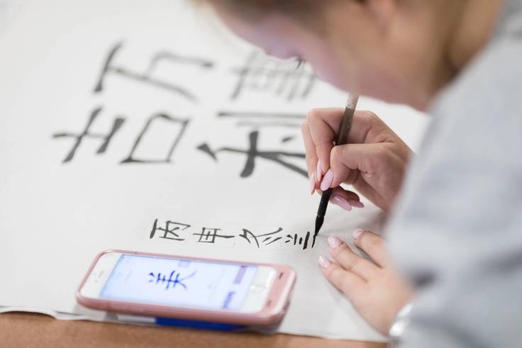 A student draws Chinese calligraphy.