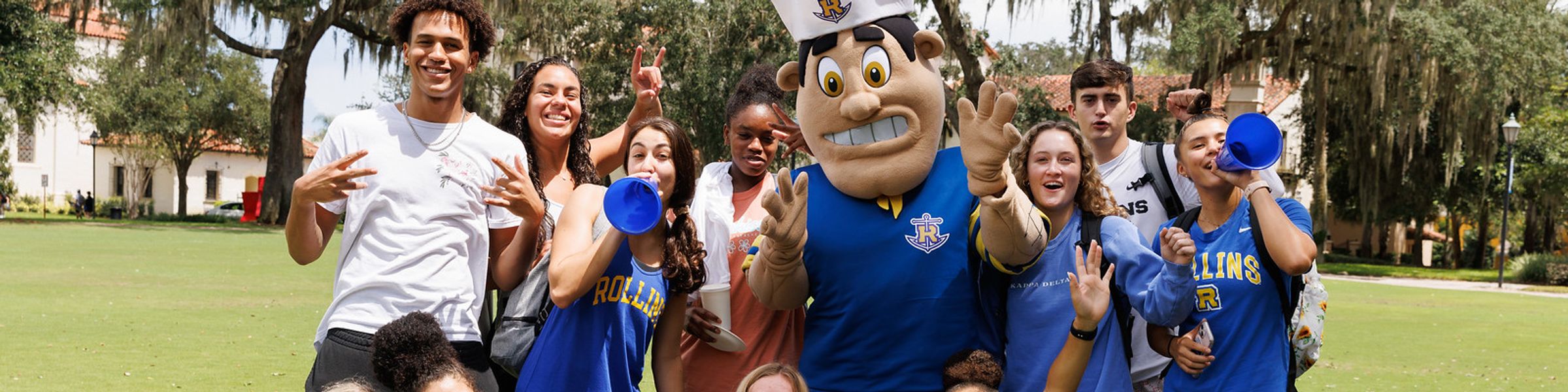 Tommy Tar mascot surrounded by students cheering with megaphones