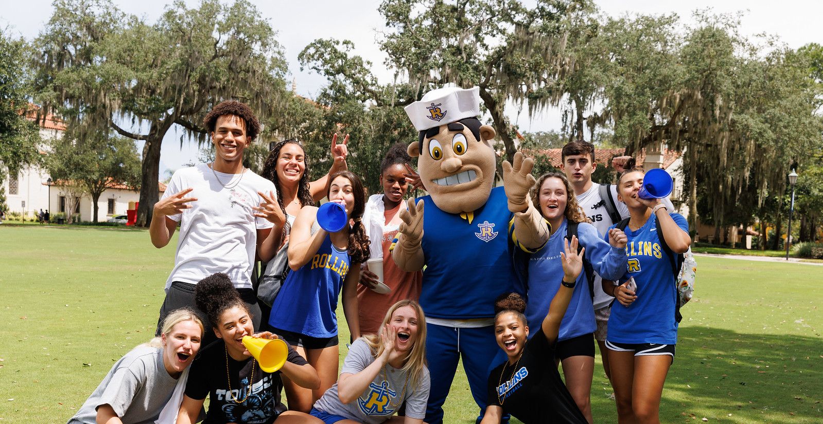 Tommy Tar mascot surrounded by students cheering with megaphones