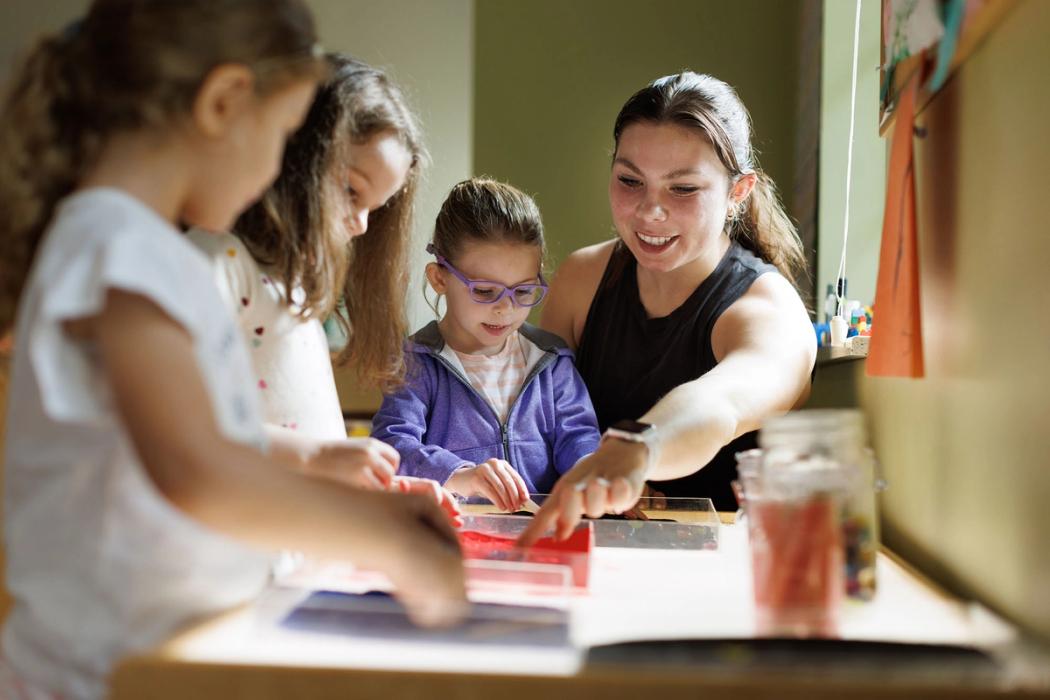 A teacher works with a group of young school children.