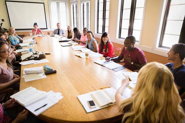 Students gather around a table during a seminar-style class session.