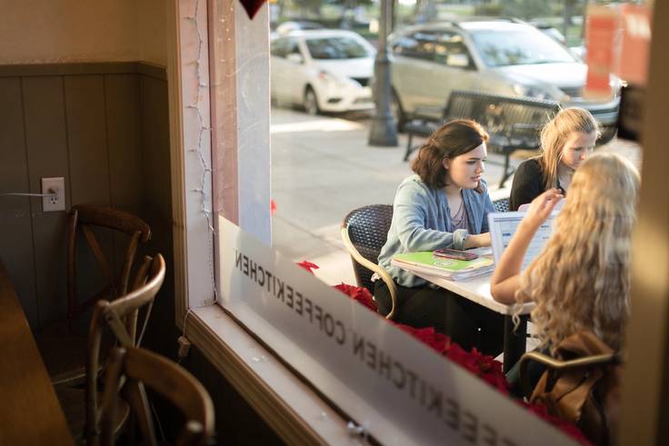 Students sit outside at Barnie’s CoffeeKitchen collaborating on blog content for the company’s website.