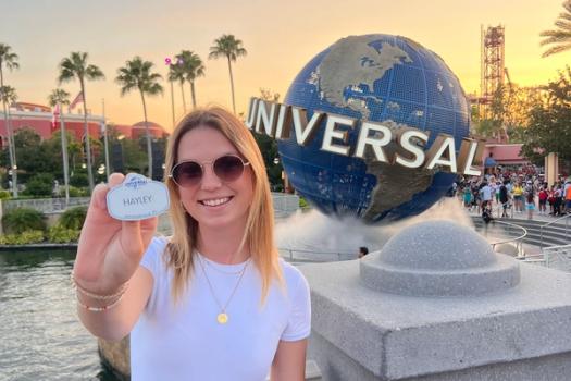 A college student poses in front of the Universal sign at Universal Orlando.