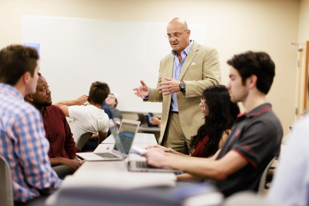 A professor explains a concept to a small group of students during a business class at Rollins College.