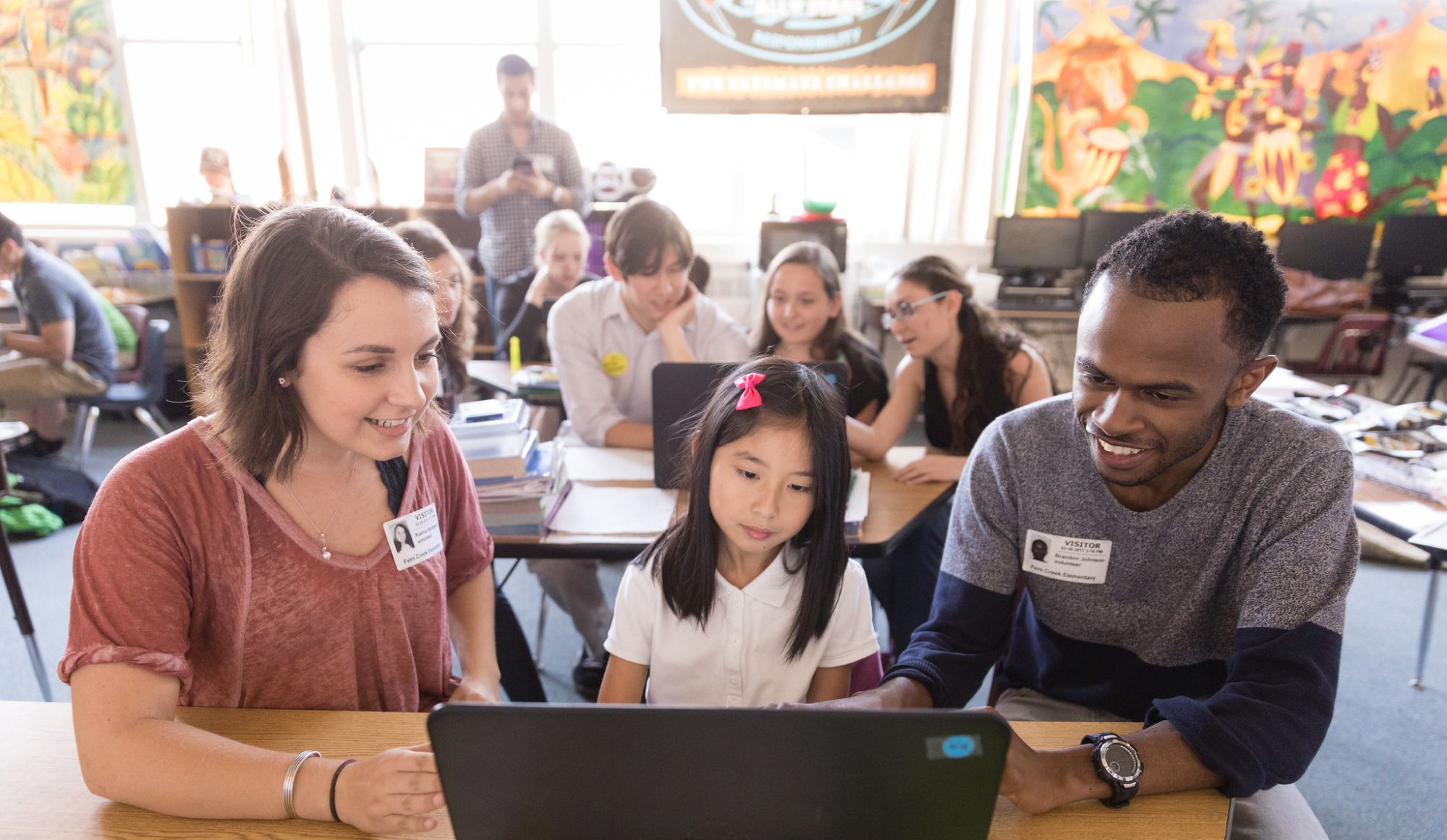 Students work with an elementary student on teaching computer skills.