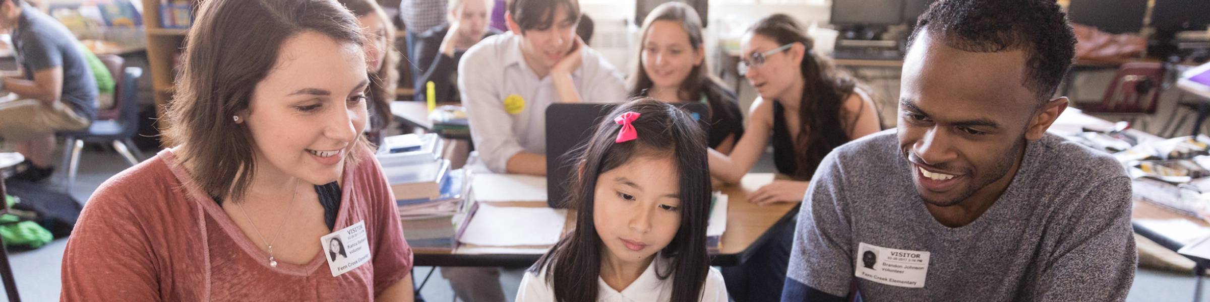Students work with an elementary student on teaching computer skills.