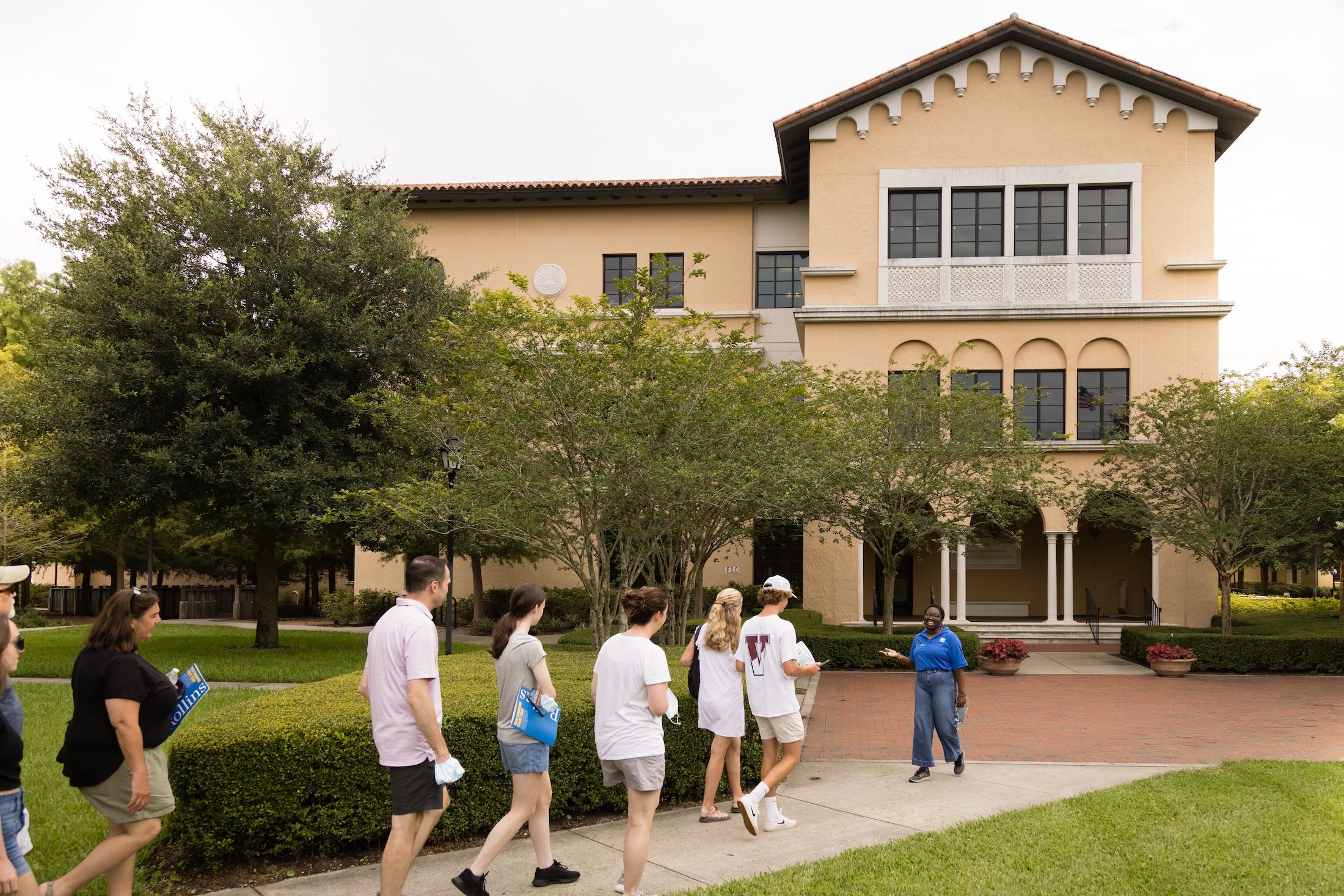 A Rollins admission tour guide walks a group of families around campus, passing in front of Bush Science Center.