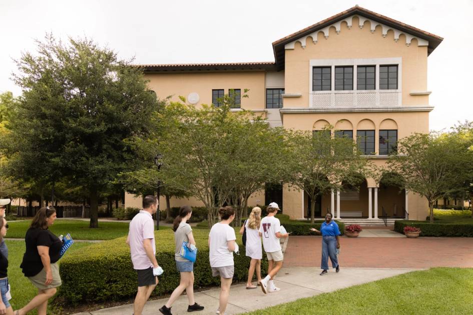 An student guide leads a group of prospective students and parents on a tour of the Rollins College campus.