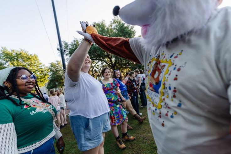 Rollins mascot Fox high-fiving students on Mills Lawn