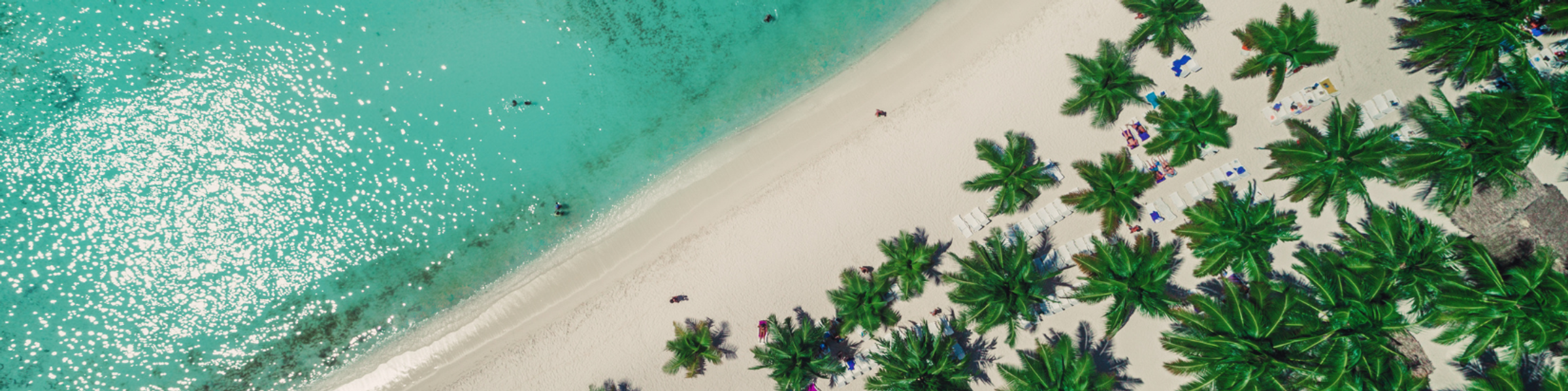 Aerial view of a beach in the Dominican Republic with blue water and palm trees
