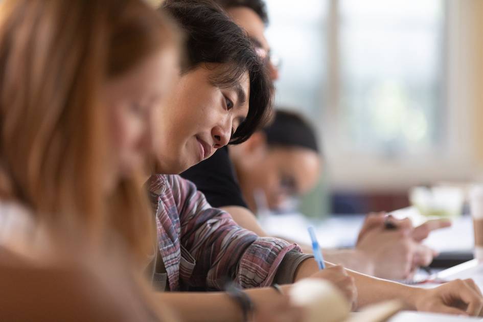 A Rollins College student takes notes while in a religious studies class.