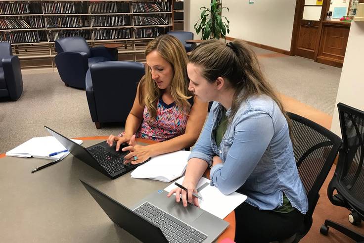 A professor and a student conduct collaborative research in Olin Library.