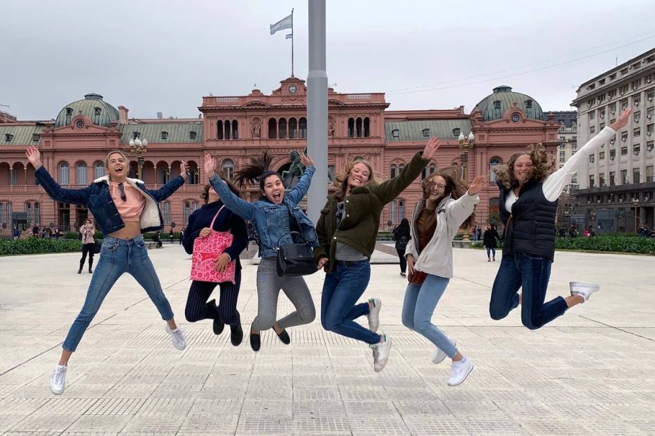 Student jumping together in a city square.