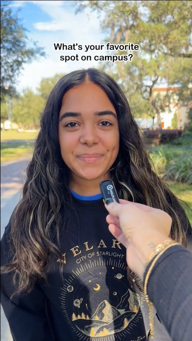 Screenshot from video of a student holding out a mic interviewing another with the title "What's your favorite spot on campus?" overhead.