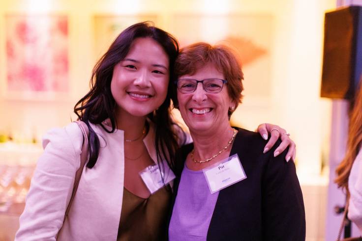 A young female professional hugs her mentor during an alumni event.