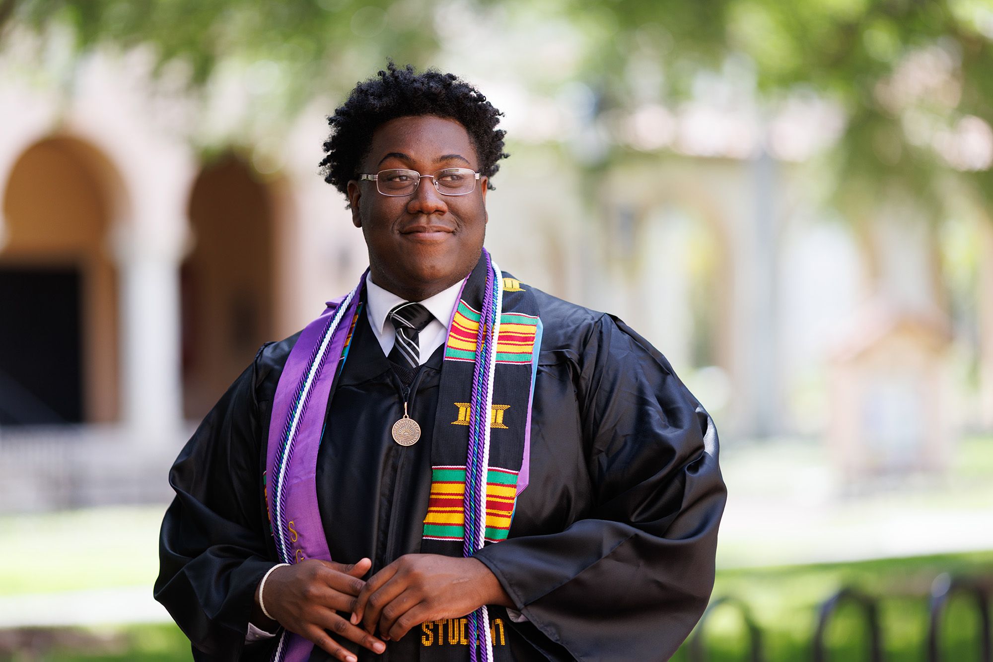 A college graduate poses on the Rollins campus.