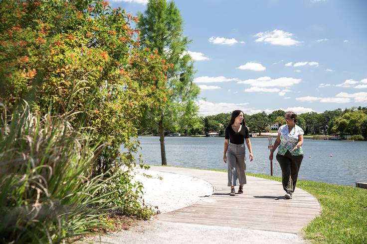 Rollins student and advisor walk on the campus path that lines Lake Virginia.