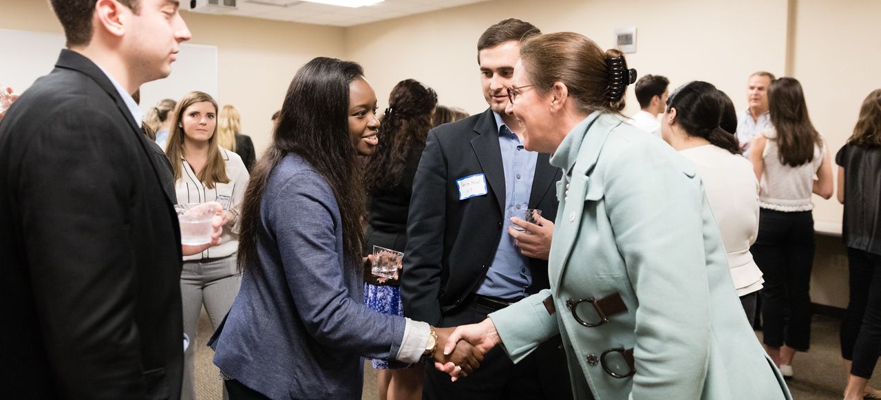 Group of young professionals shaking hands with an executive.