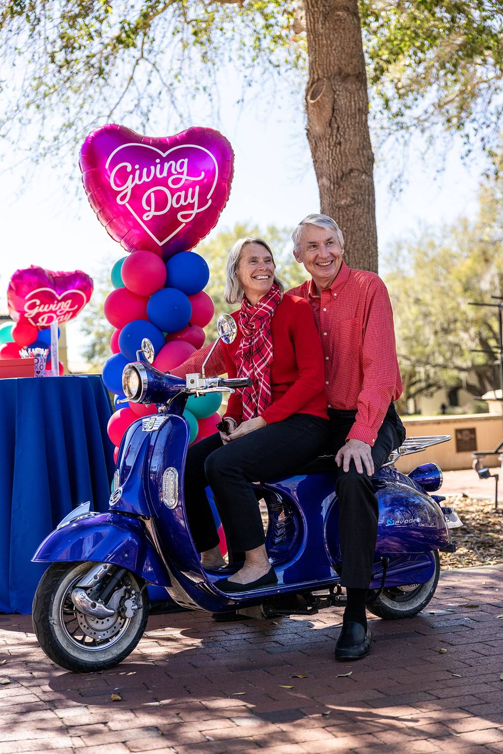 Grant and Peg Cornwell posing on a scooter on Giving Day 2024