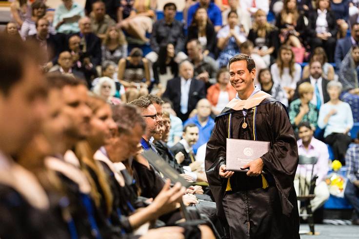 A student smiles after receiving his college diploma.