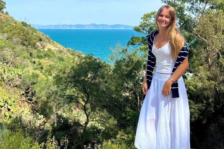 Kaylin Pung ’28 standing on lush coastal hillside overlooking bright blue ocean