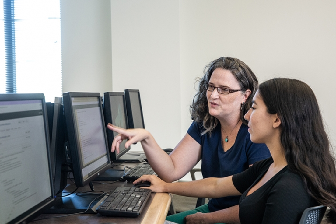 Teacher pointing at computer screens to show student an area on the screen.