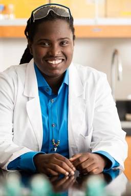 A biochemistry student poses for a portrait in a lab.
