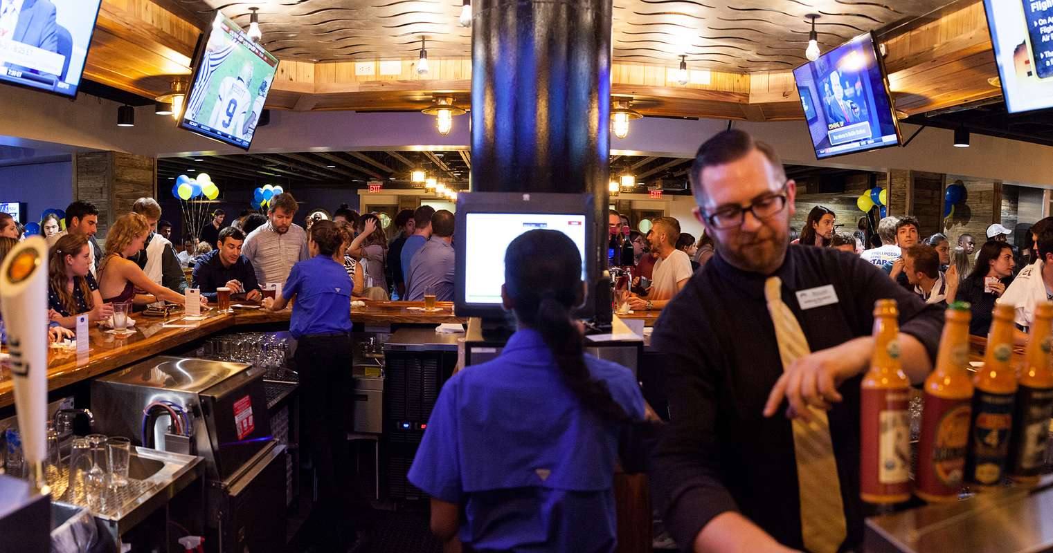Bartenders serve beer and food in Dave’s Boathouse.