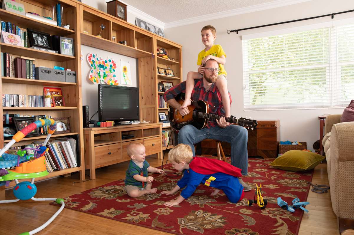 Dan Myers playing a guitar surrounded by his kids.