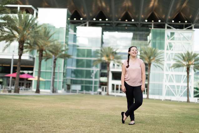 A student with an internship standing in front of the Dr. Phillips Performing Arts Center.