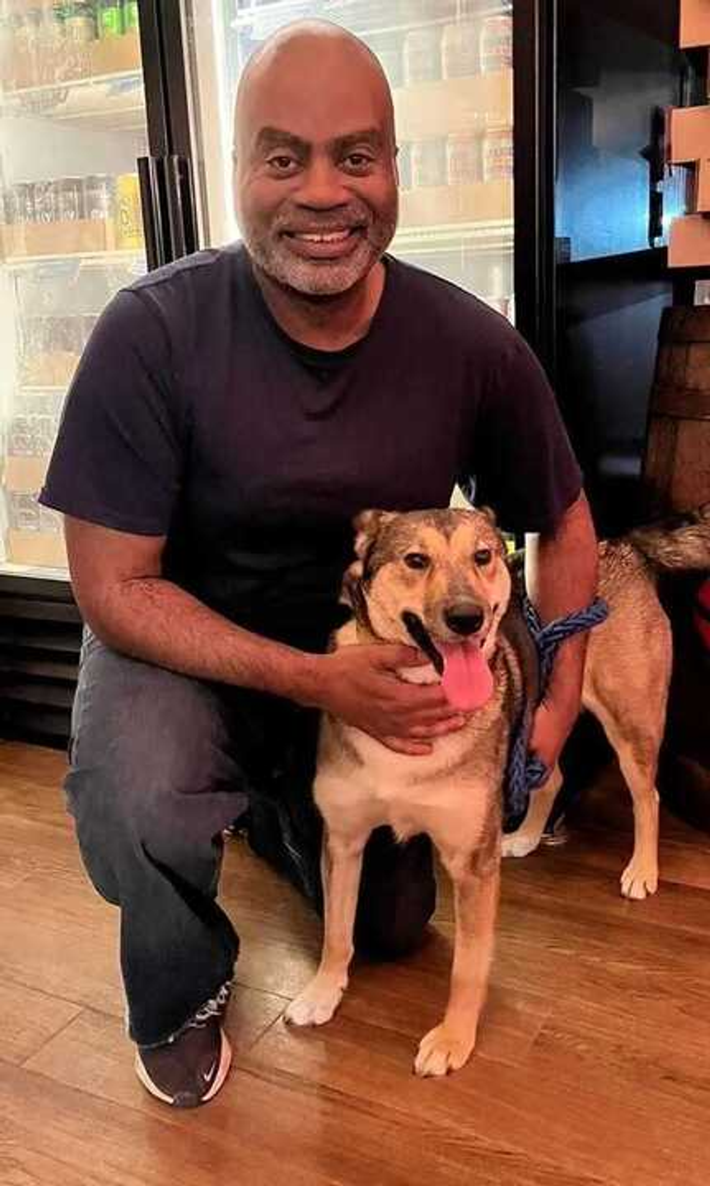 Rad kneeling next to a rescue dog, smiling at the camera