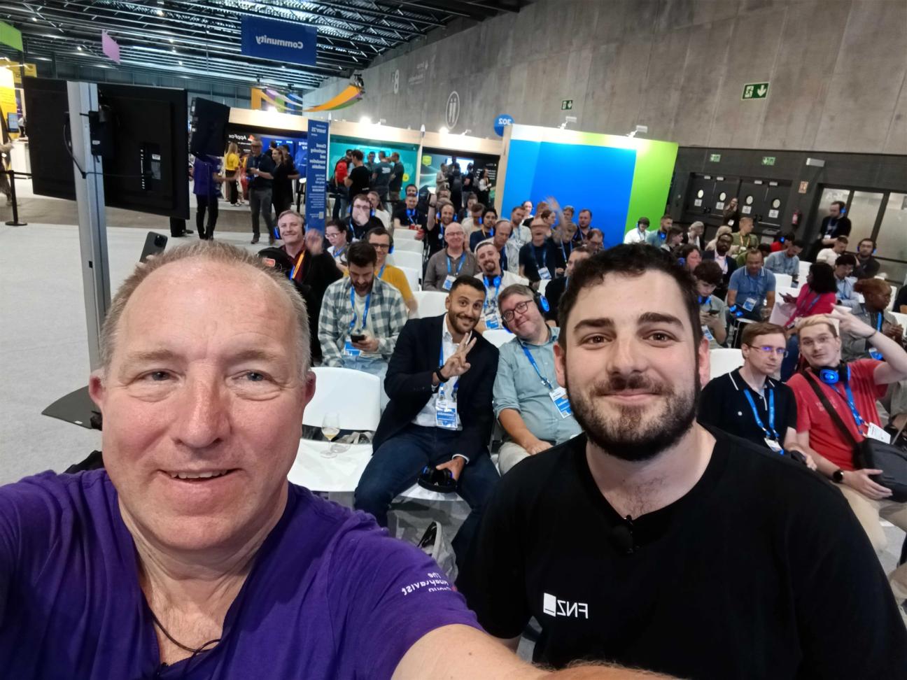 Two people taking a selfie in front of the attendees at a theatre session at Team '25 Europe