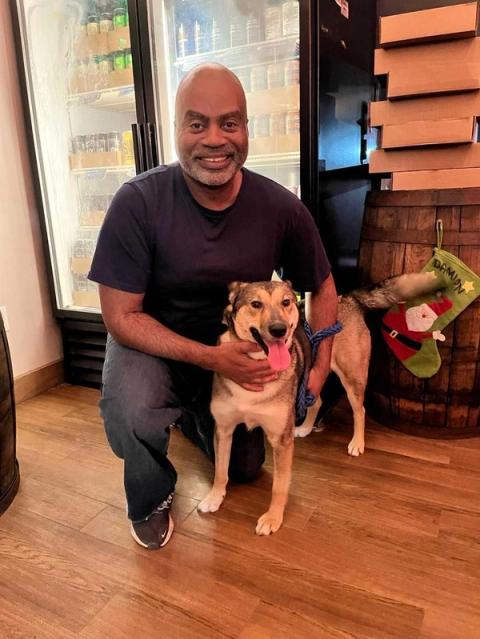 Radcliffe kneeling with his arm around a dog, smiling at the camera