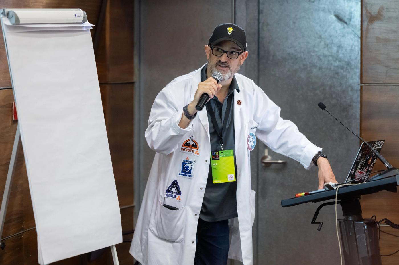 Dr Nick speaking into a microphone standing next to a flipchart