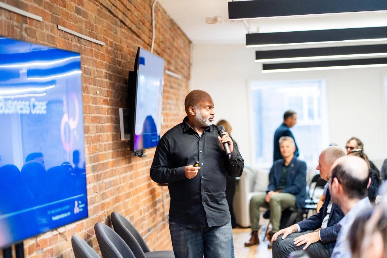 Rad Dockery holding a microphone and addressing the audience at the graduation ceremony