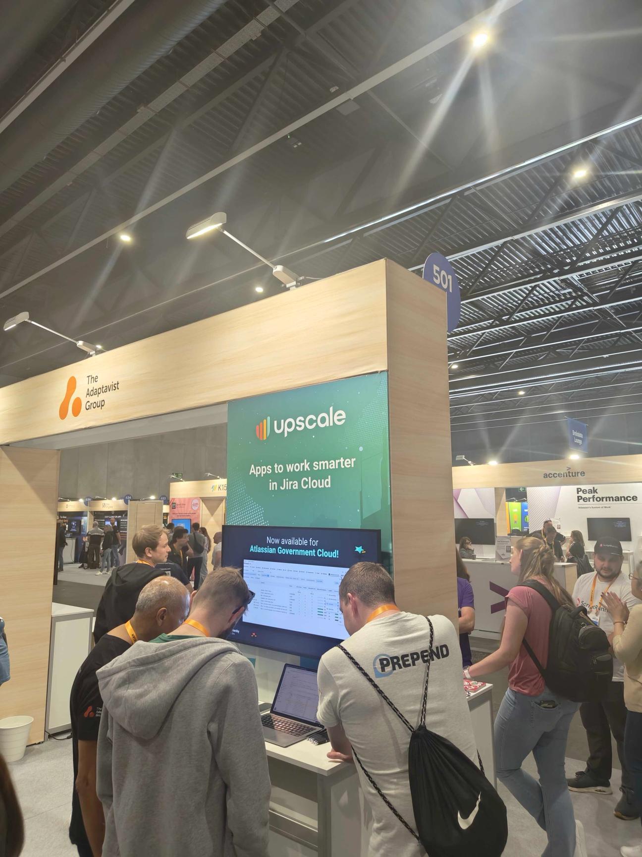 People crowding around a lap top at the Upscale Team '25 Europe booth