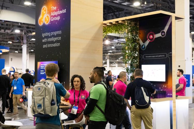 People having a discussion around The Adaptavist Group's booth at an event