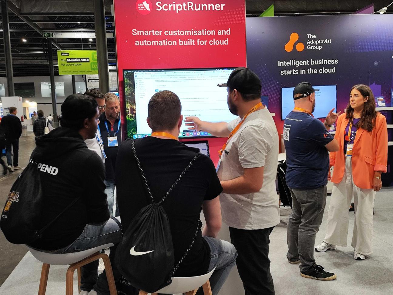 Three people around a screen at a ScriptRunner booth at Team '25 Europe
