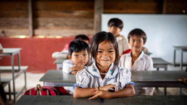 Young children sitting at classroom desks smiling