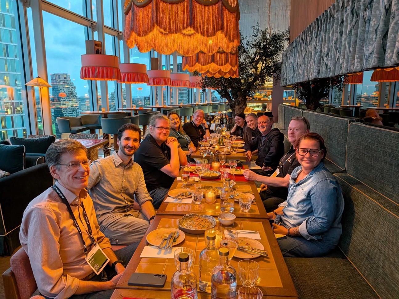 A group of people smiling at a table at a restaurant enjoying their dinner