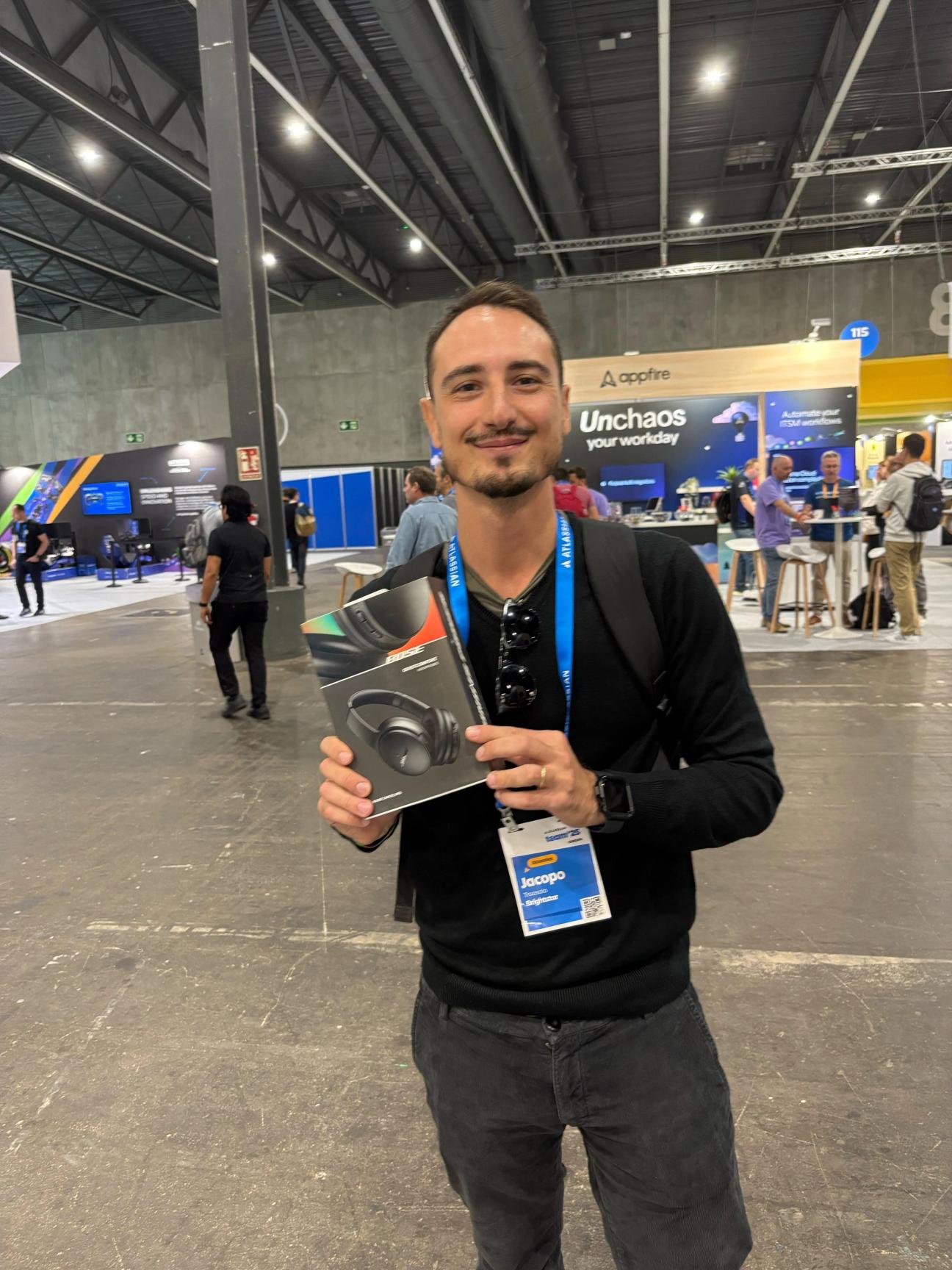 Person at Team '25 Europe smiling while holding boxed headphones they won