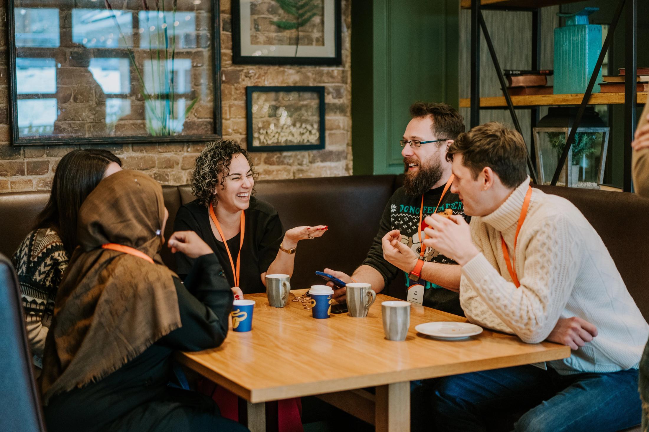 Five people talking and laughing around a table